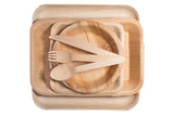 Birch wood fork, knife, and spoon on palm leaf dishes